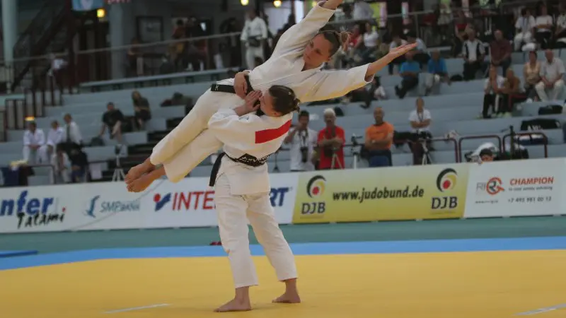 Judocas treinando queda em tatame durante prática de judô