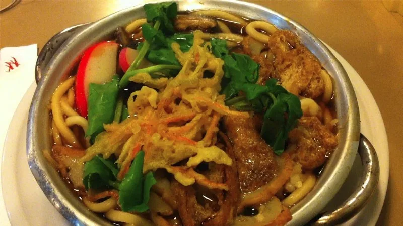 Ciotola di noodles udon con topping e brodo giapponese chiaro