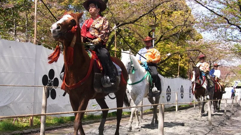 Cavaleiro em vestimenta tradicional samurai disparando contra um alvo a galope