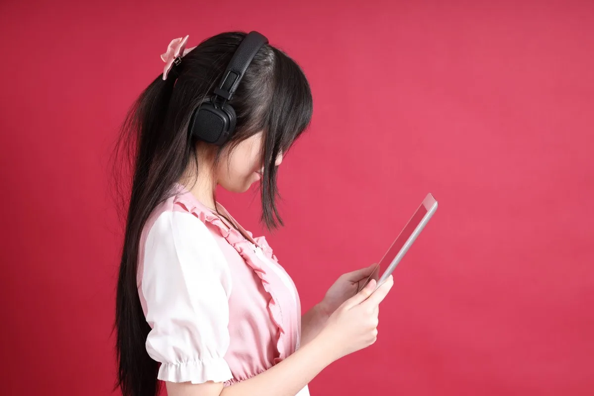 Pessoa ouvindo conteúdo japonês no celular como apoio para transcrição e estudo