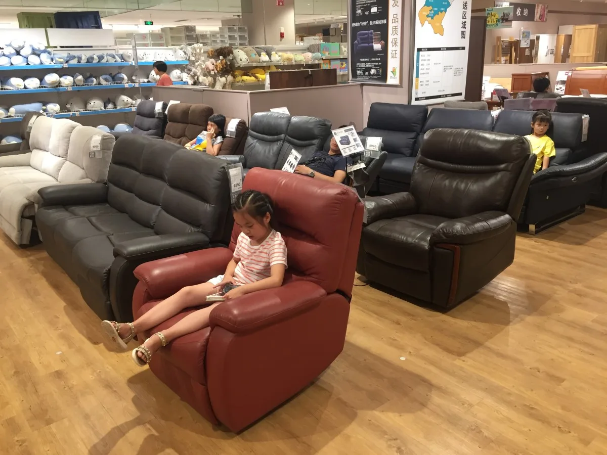 Local Chinese residents sleep or rest on sofas at a store of Japanese furniture and home accessory retailer Nitori in Wuhan city, central China's Hubei province, 15 July 2018
