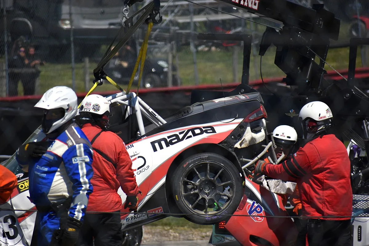 Race officials clearing a wrecked MX-5 from the track.