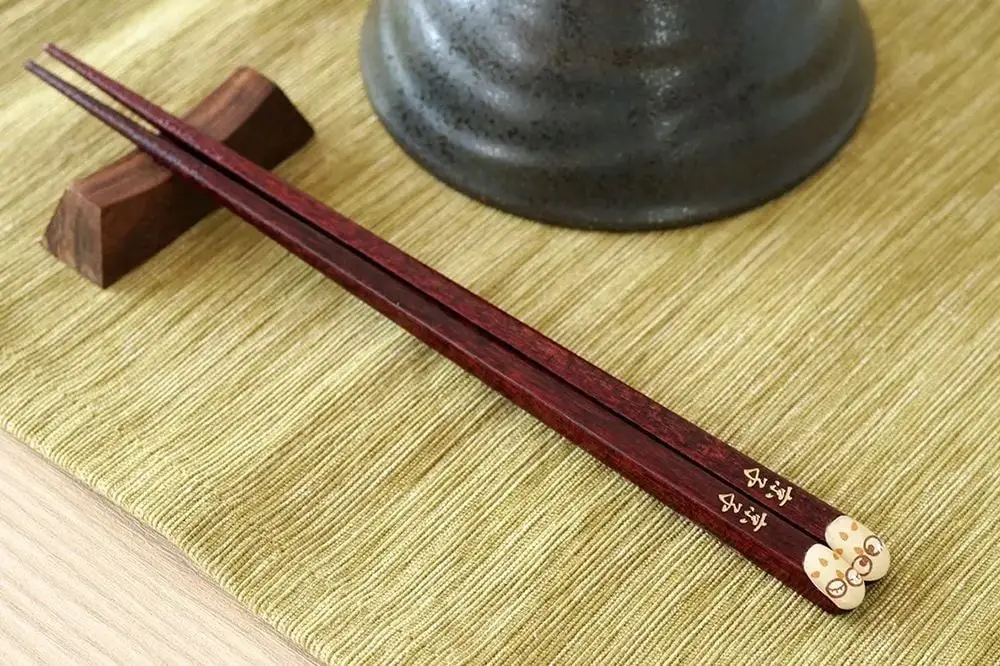 Pessoa segurando hashi em contexto asiático de refeição